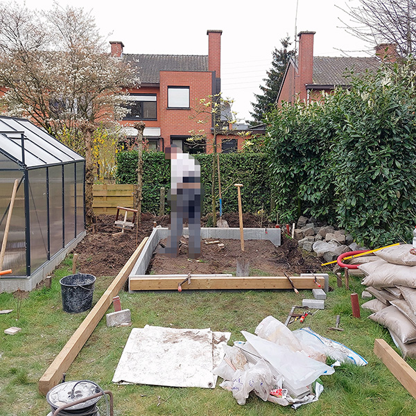 building materials in a garden, next to a green house, pixelated figure standing in the middle