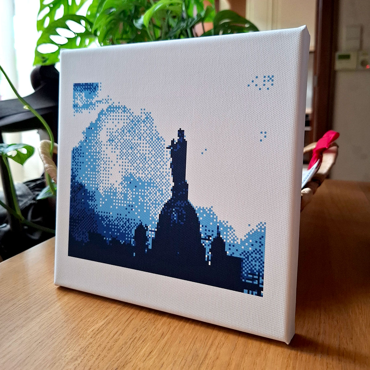 print of a pixel photo on canvas, standing in front of a monstera plant and on a wooden table