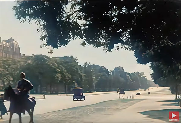 a street in Paris in the twenties, with old cars, a man on a horse, trees ligning the street